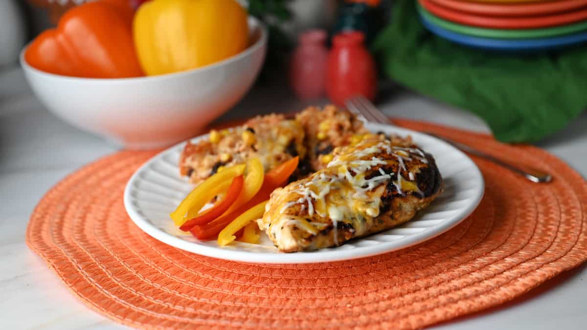 A plate with fajita stuffed chicken served with brown rice and black beans bake.
