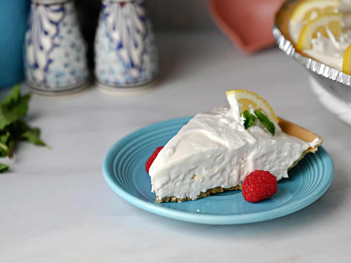 A slice of lemonade pie on a small blue plate.
