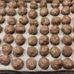 a sheet pan of cooked meatballs made for meal prep and ready to transfer to the freezer.