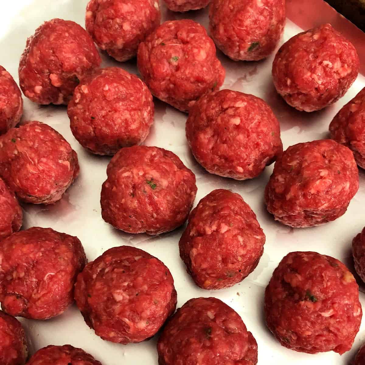 uncooked meatballs on a baking sheet