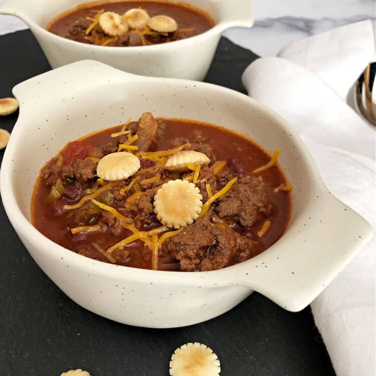 bowl of old fashioned chili with a little shredded cheese and crackers on top
