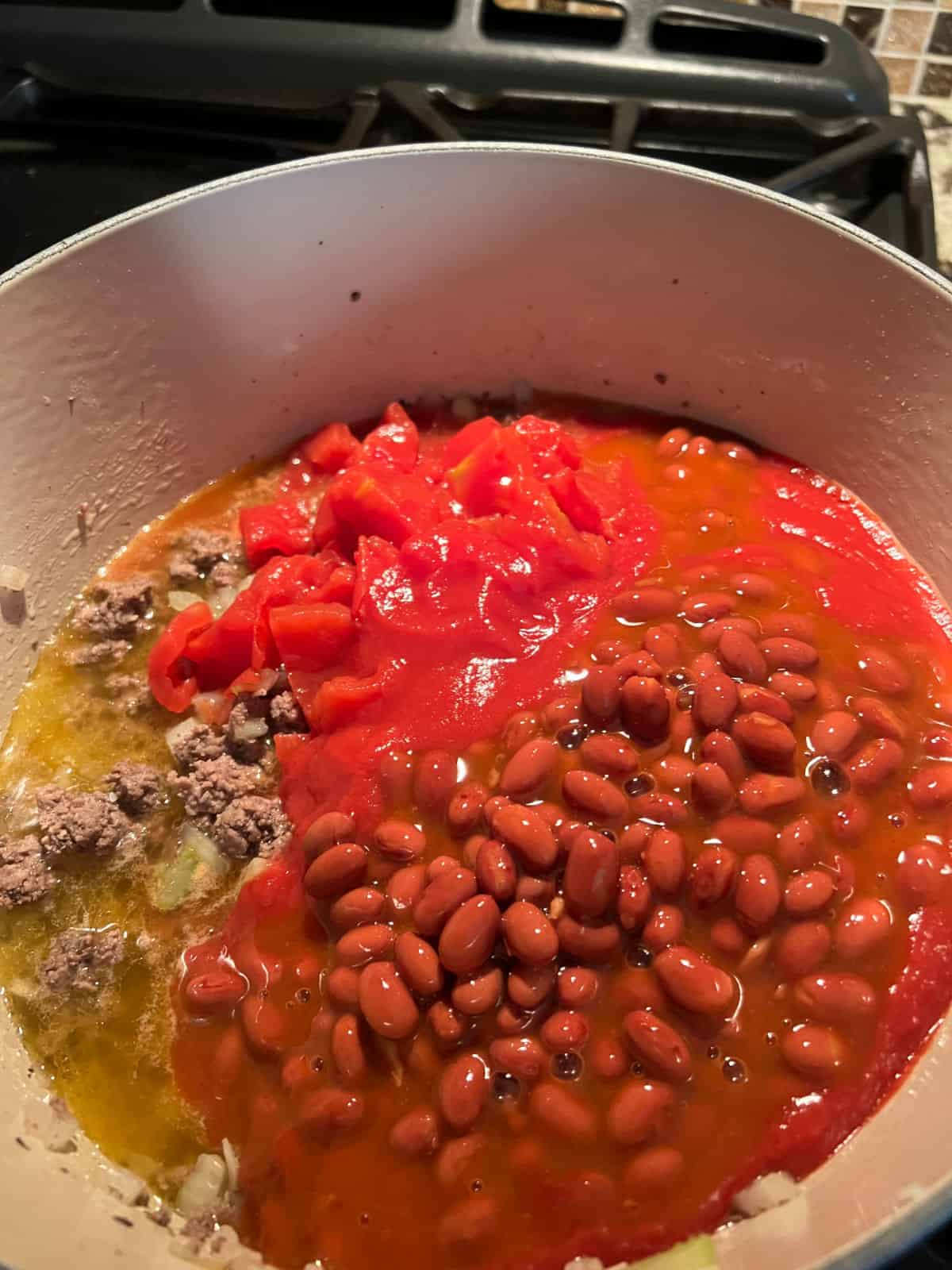 adding tomatoes and beans to the pot.