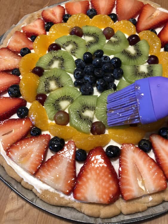 Brushing fruit pizza with jelly