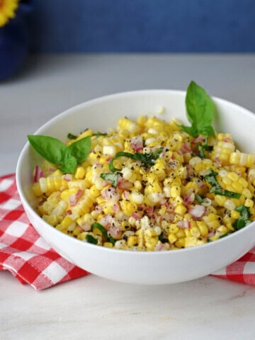 a white serving bowl of fresh corn salad.