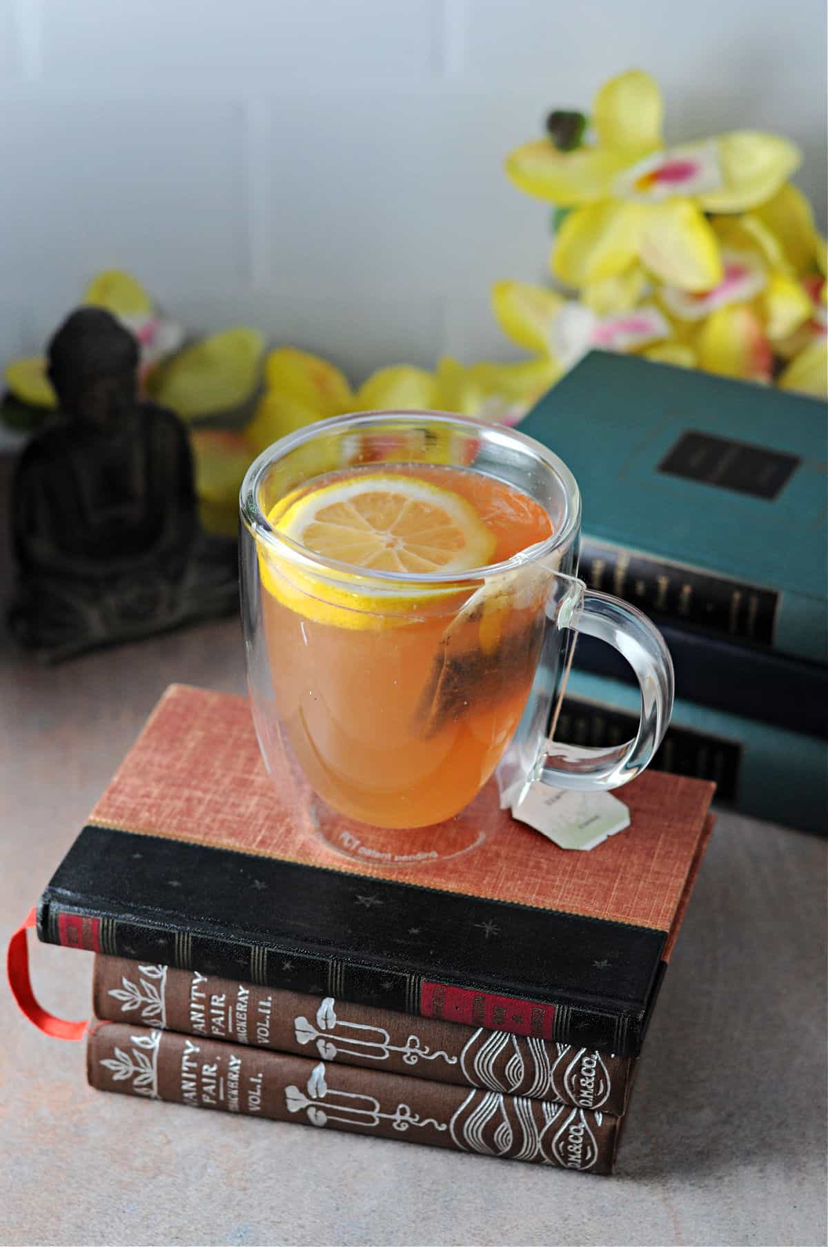 A cup of medicine ball tea on top of a stack of books.