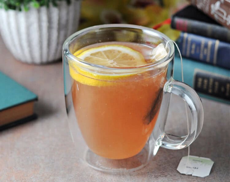 a Clear mug filled with tea, with a lemon slice floating on top.
