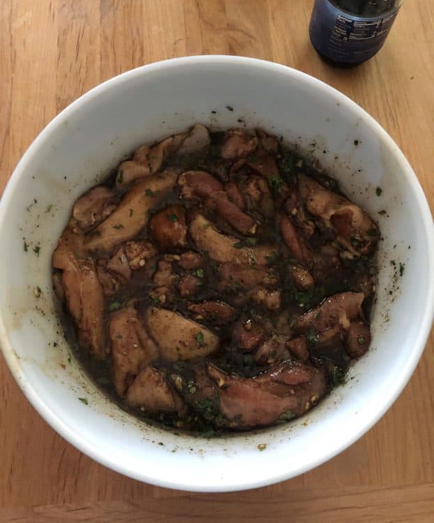 meat in marinade in a white bowl
