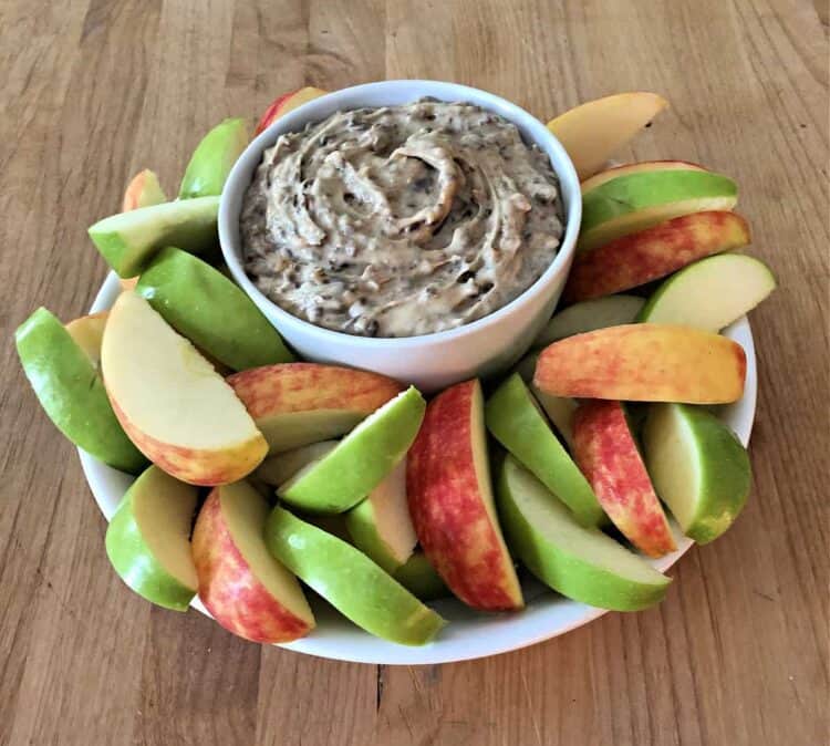 bowl of heath bar dip surrounded by slices of red and green apple