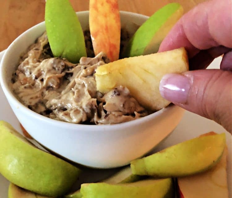 hand holding an apple slice dipping into heath bar dip