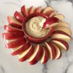 greek yogurt with peanut butter dip surrounded by apple slices