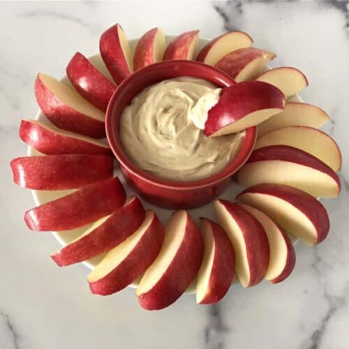 greek yogurt with peanut butter dip surrounded by apple slices