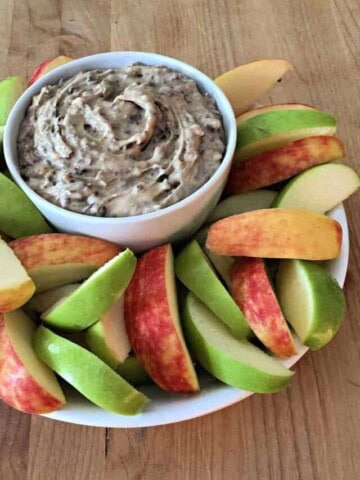 bowl of heath bar apple dip surrounded by slices of red and green apple