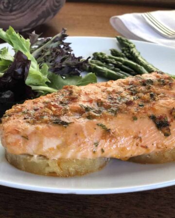 baked pineapple salmon on a white plate with salad and asparagus