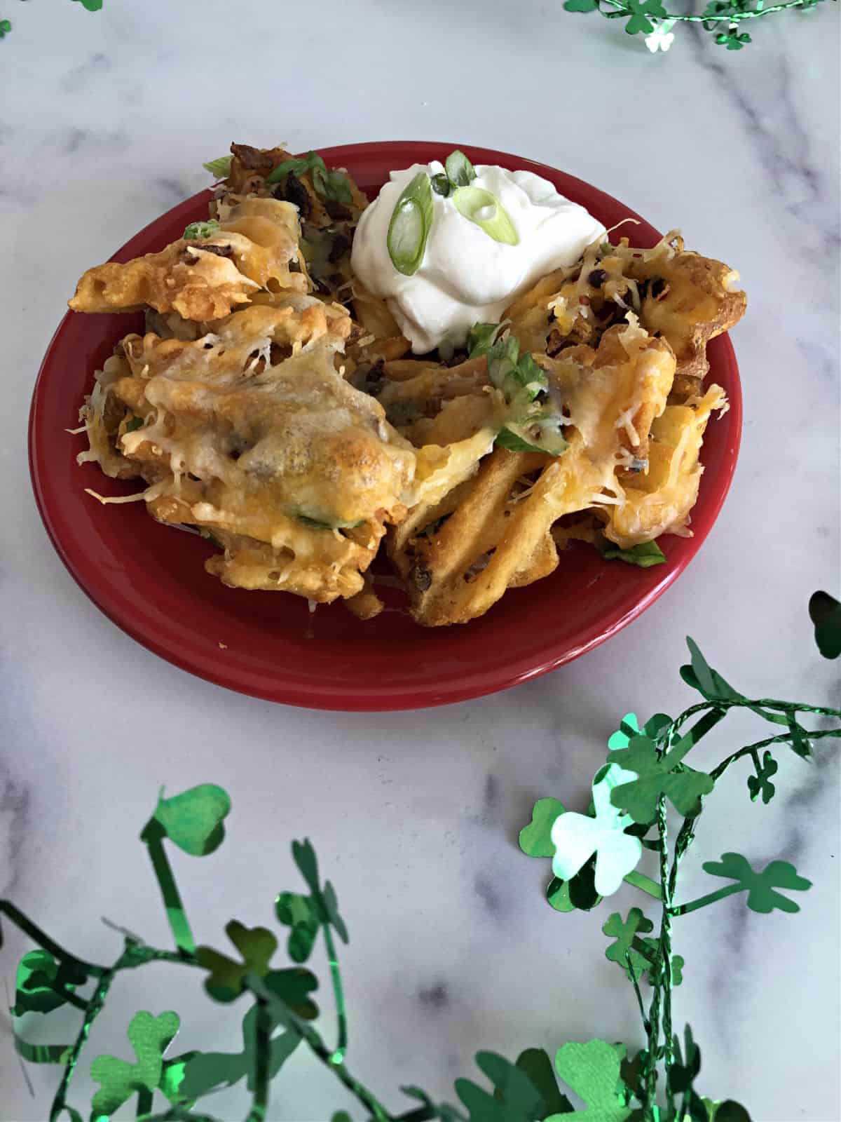 Plate of Irish Nachos with sour cream, ready to eat.