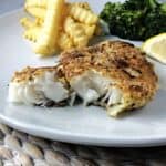 Potato crusted cod on a white plate.