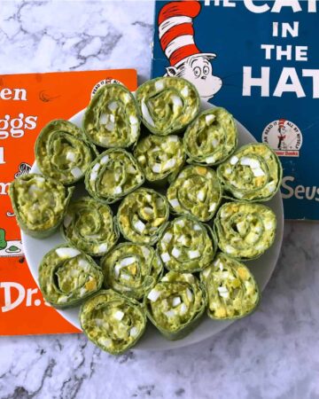 Egg salad pinwheels on a white plate with Dr Seuss books behind