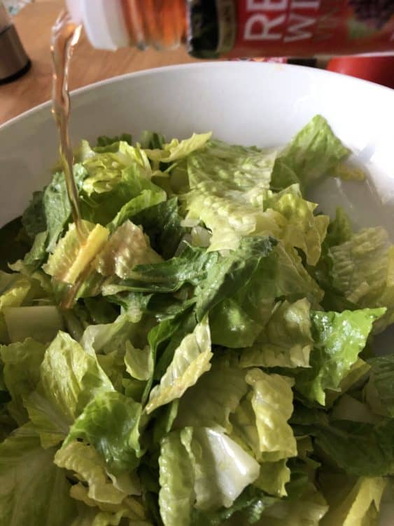 adding vinegar to salad in a bowl