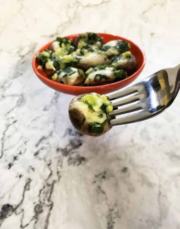 fork holding a brie stuffed mushroom