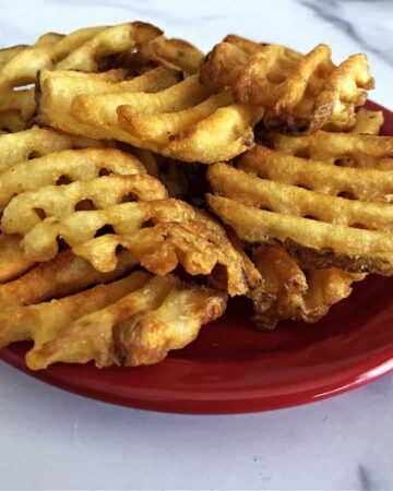 Waffle fries on a small red plate