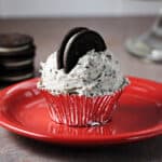 Cupcake with Oreo Buttercream frosting on a red plate.
