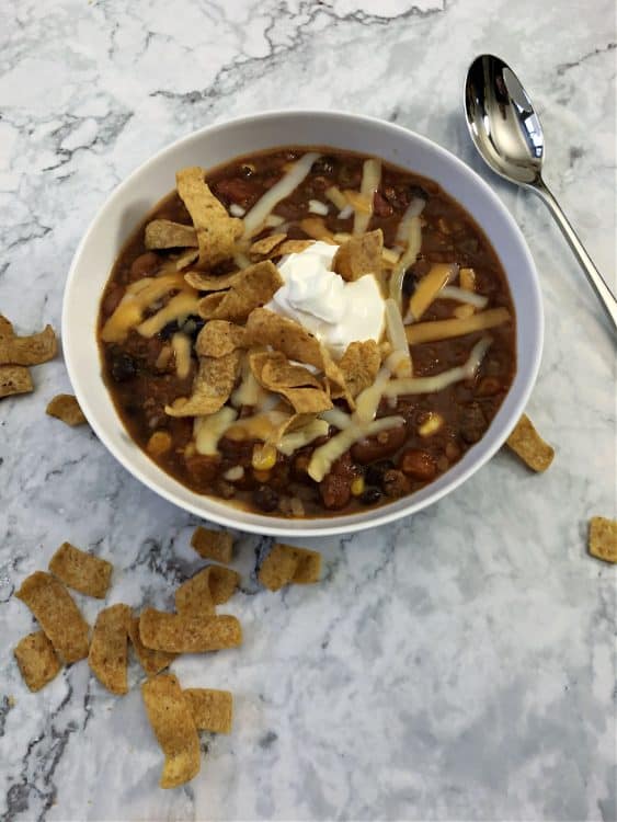taco chili in a bowl topped with cheese, chips and sour cream
