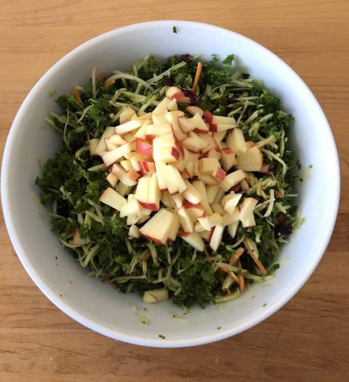 chopped apples added to the salad in a bowl