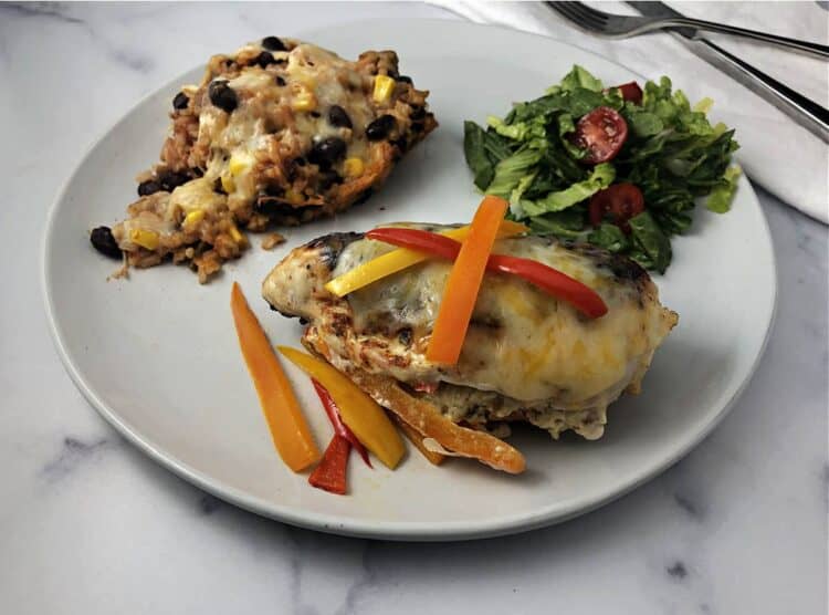 Fajita stuffed chicken on a plate with rice and a salad