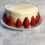 Layer cake frosted with white froating and decorated with fresh strawberries