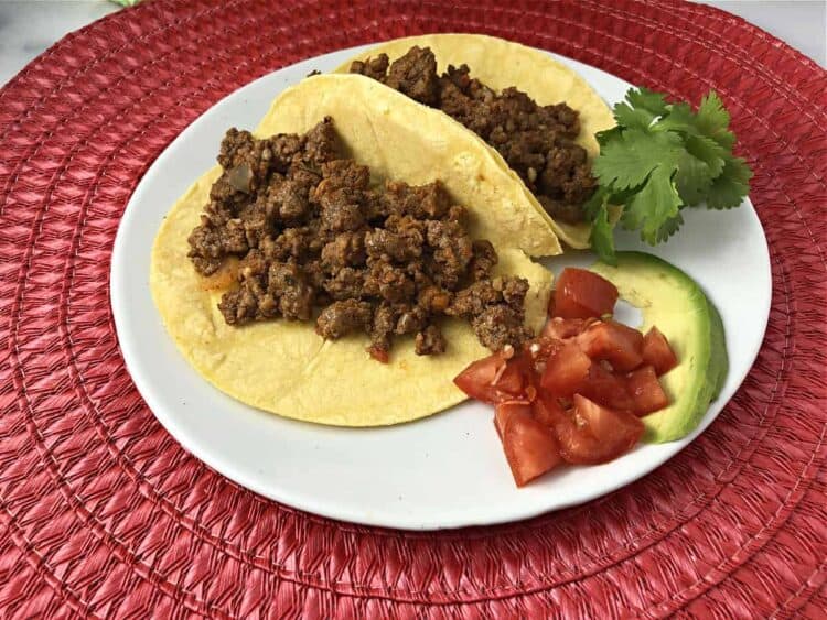 taco meat in small corn tortillas on a small plate