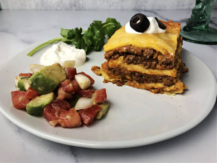 burrito pie on a plate with salsa and sour cream