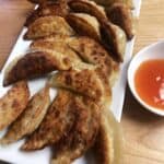 serving platter of potstickers with some dipping sauce