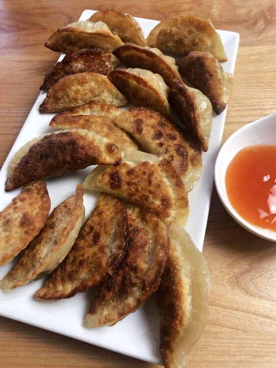 serving platter of potstickers with some dipping sauce