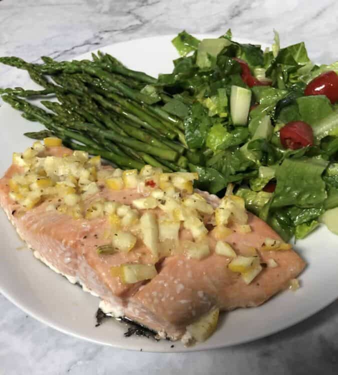 salmon with lemon dressing on a plate with asparagus and salad