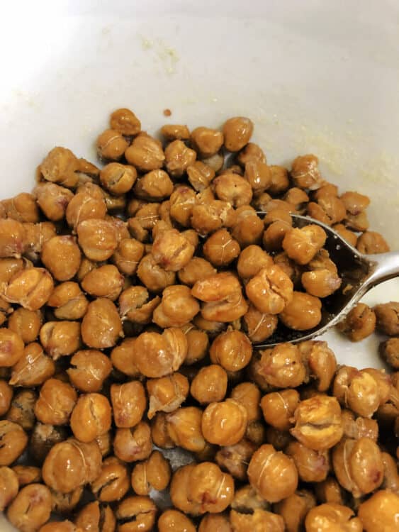 dry roasted chickpeas in a bowl stirring with oil and salt