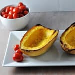 grilled spaghetti squash on a plate with grape tomatoes nearby