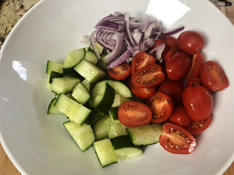 cut up tomatoes, cucumber and red onion in a bowl