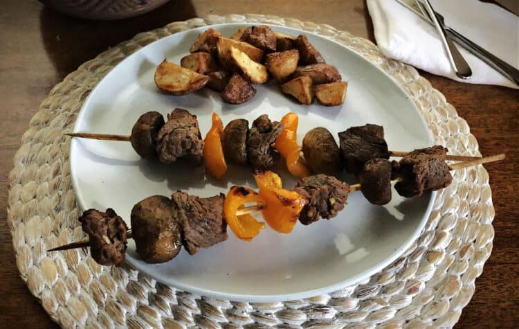 beef kabobs on a plate with potatoes