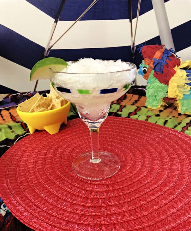 a margarita glass full of the icy slush, surrounded by bright colors and some chips