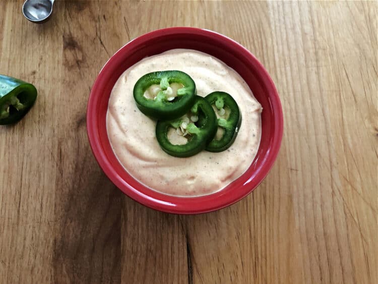 small red bowl with quesadilla sauce garnished with jalapeno slices