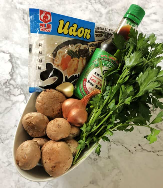 ingredients for soup: mushrooms, noodles, shallot, garlic, soy sauce, fresh herbs