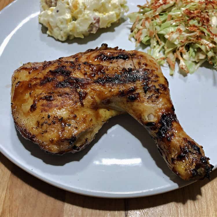 grilled chicken quarter on a white plate with salads