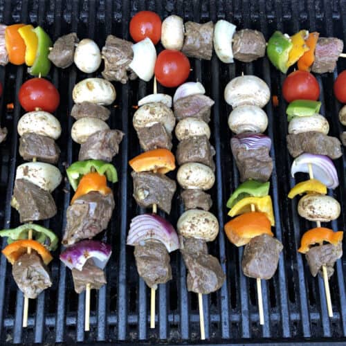 Beef kabobs cooking on a grill.