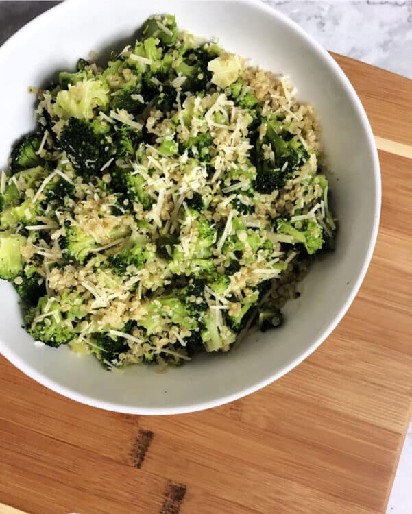 quinoa broccoli parmesan in a white bowl on a cutting board