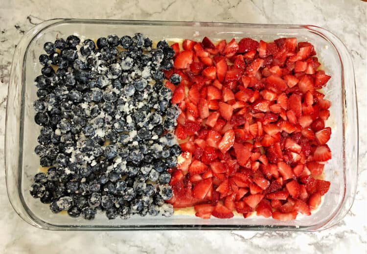 top down view of 9x13 pan layered half with blueberries and the rest with strawberries