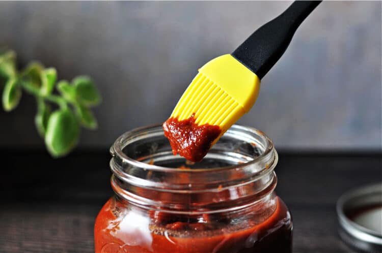 yellow basting brush containing keto BBQ sauce dipped from the jar
