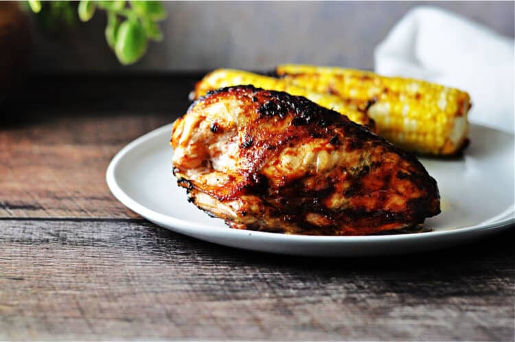 Keto BBQ chicken breast on a plate with corn on the cob