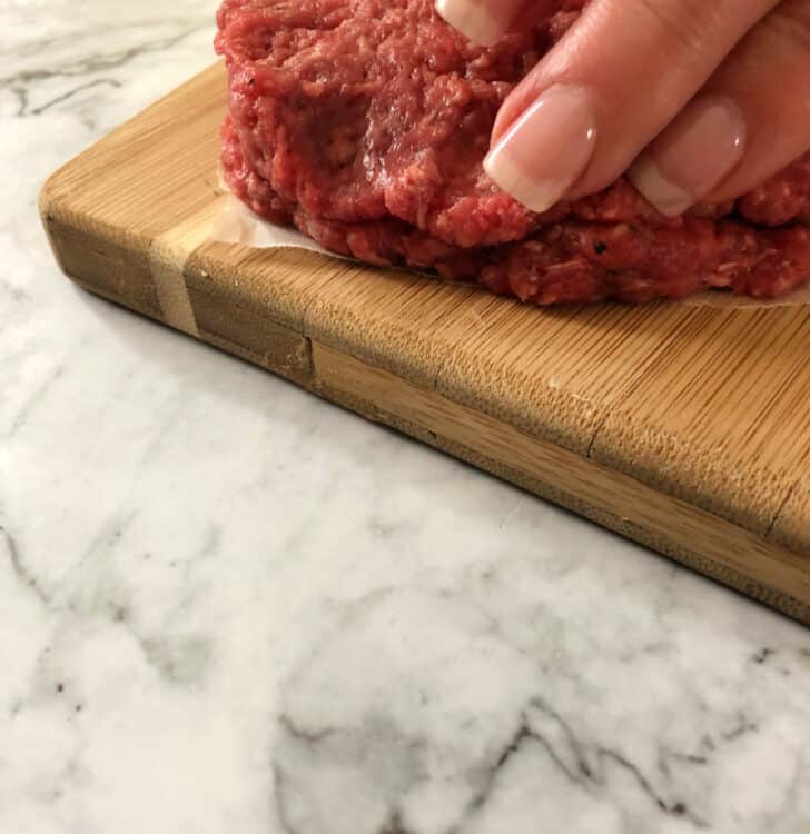 fingers sealing the edges of the 2 patties together