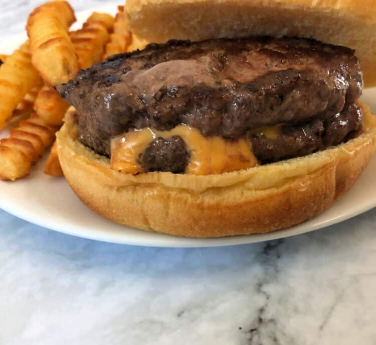 stuffed hamburger on a bun with cheese oozing from the center