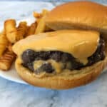 Juicy lucy stuffed burger with extra cheese on top and some cheese oozing from the burger