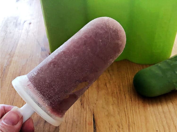 hand holding a berry colored smoothie popsicle